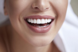 Close-up of a woman smiling with straight, bright white teeth and healthy gums.